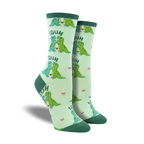 A pair of green Socksmith Hugs Crew Socks Mint - Womens with a dinosaur design and the word "Socksmith Hugs" printed on them, displayed on a plain background.