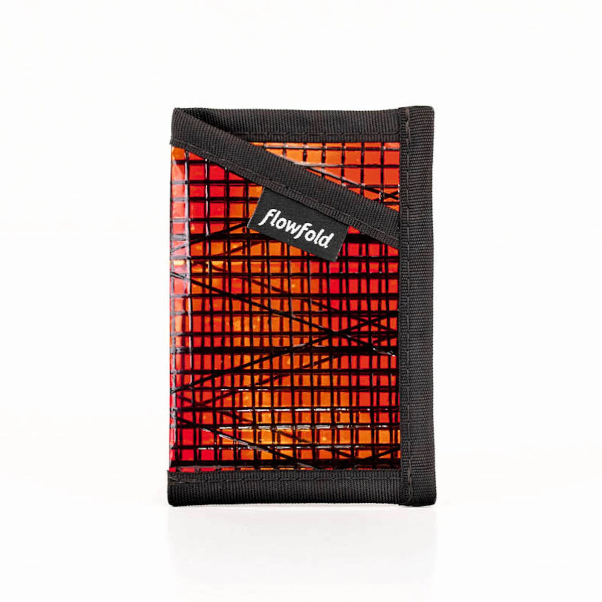 A red and black Flowfold Minimalist Sunset sailcloth wallet, made from recycled racing sails, against a white background.