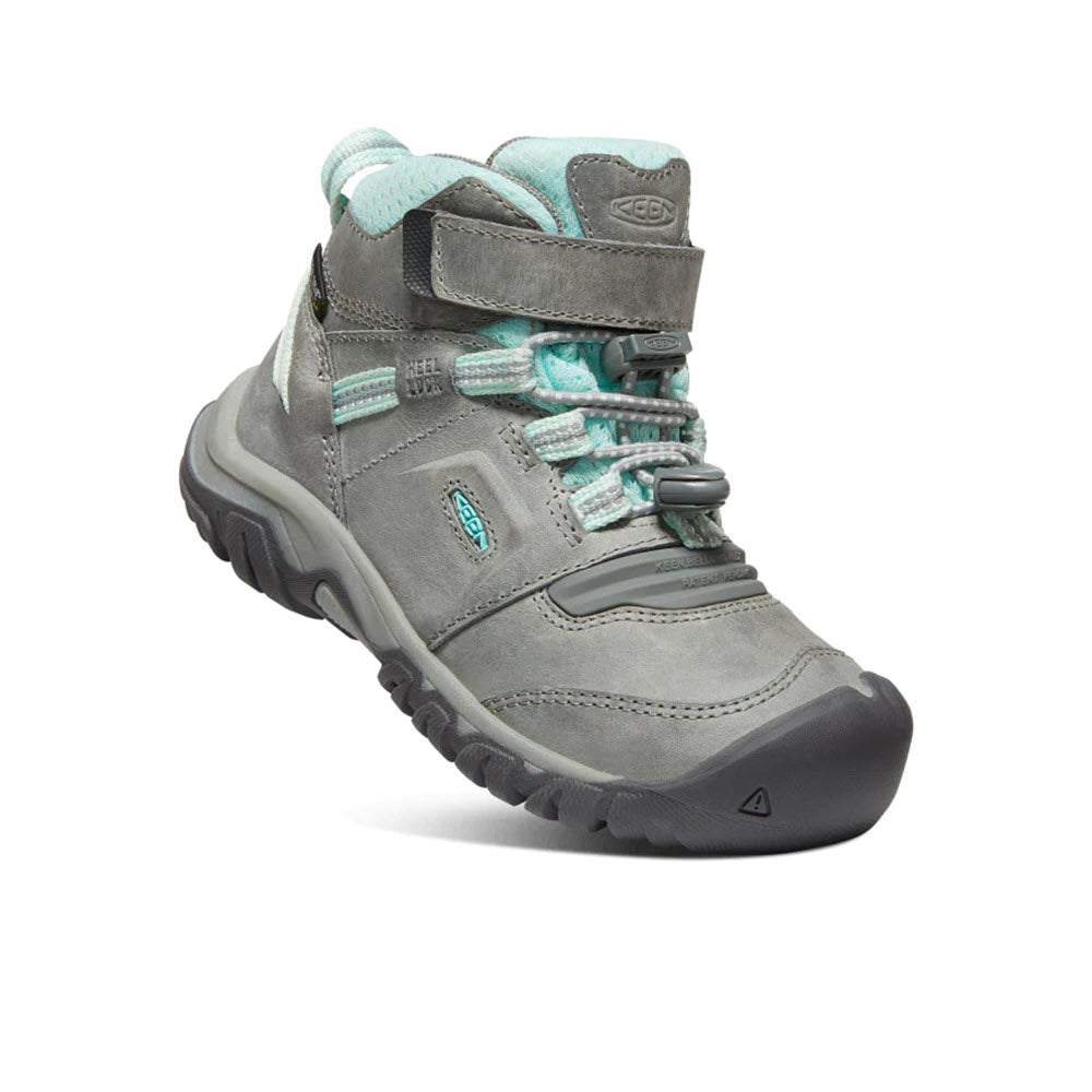 A grey hiking boot with teal laces and accents, featuring a rugged sole and a padded collar, with a Keen logo on the side.