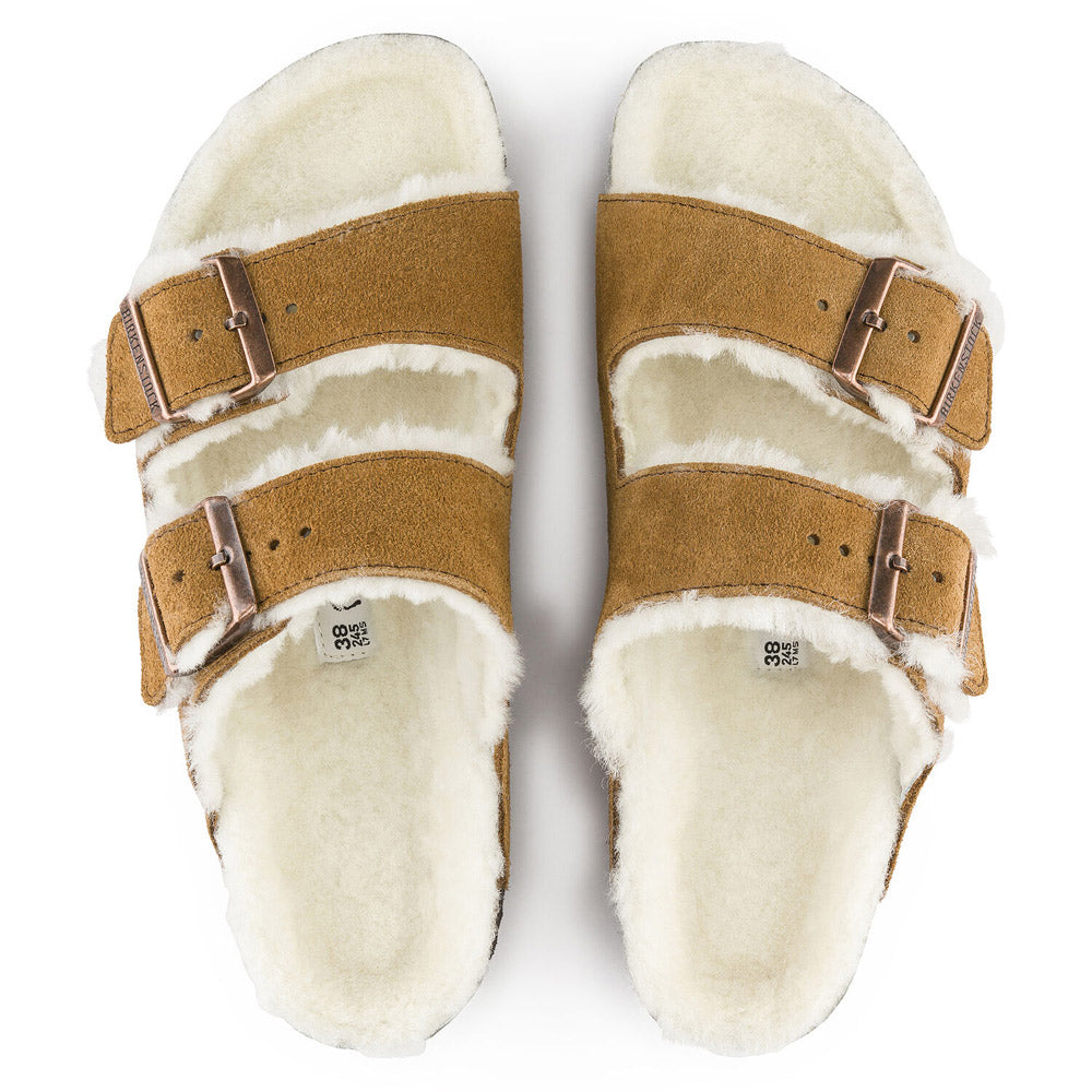 A pair of fuzzy, cream-colored Birkenstock Arizona Shearling Mink open-toed slippers with adjustable brown straps.