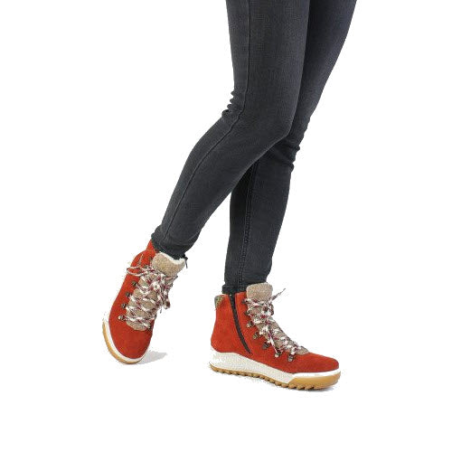 A person wearing black leggings and red Rieker Lightweight Urban Hiker with Fur Red boots against a white background.