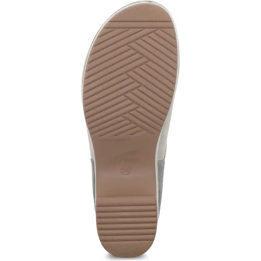 Bottom view of a Dansko Brenna Taupe Burnished - Womens clog displaying a tan rubber sole with a herringbone pattern and embossed brand details.