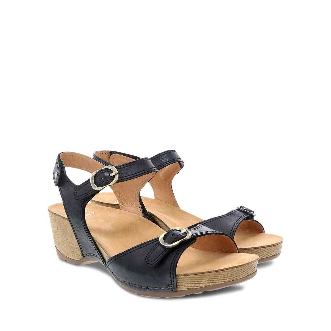 A pair of black women&#39;s open-toe Dansko Tricia Black Milled Burnished sandals with leather linings, against a white background.