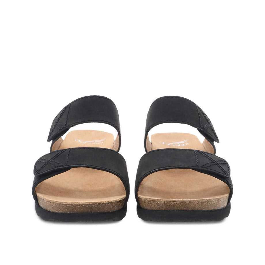A pair of black Dansko Maddy slide sandals with leather uppers and cork footbeds against a white background.