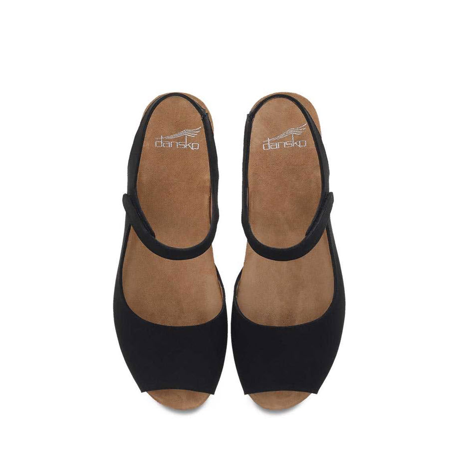 A pair of black mary jane style Dansko Marcy Wedge shoes with a brown insole, viewed from above.