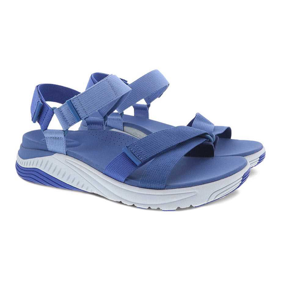 A pair of Dansko Racquel Blue Multi Webbing sports sandals with adjustable straps and a supportive EVA midsole on a white background.