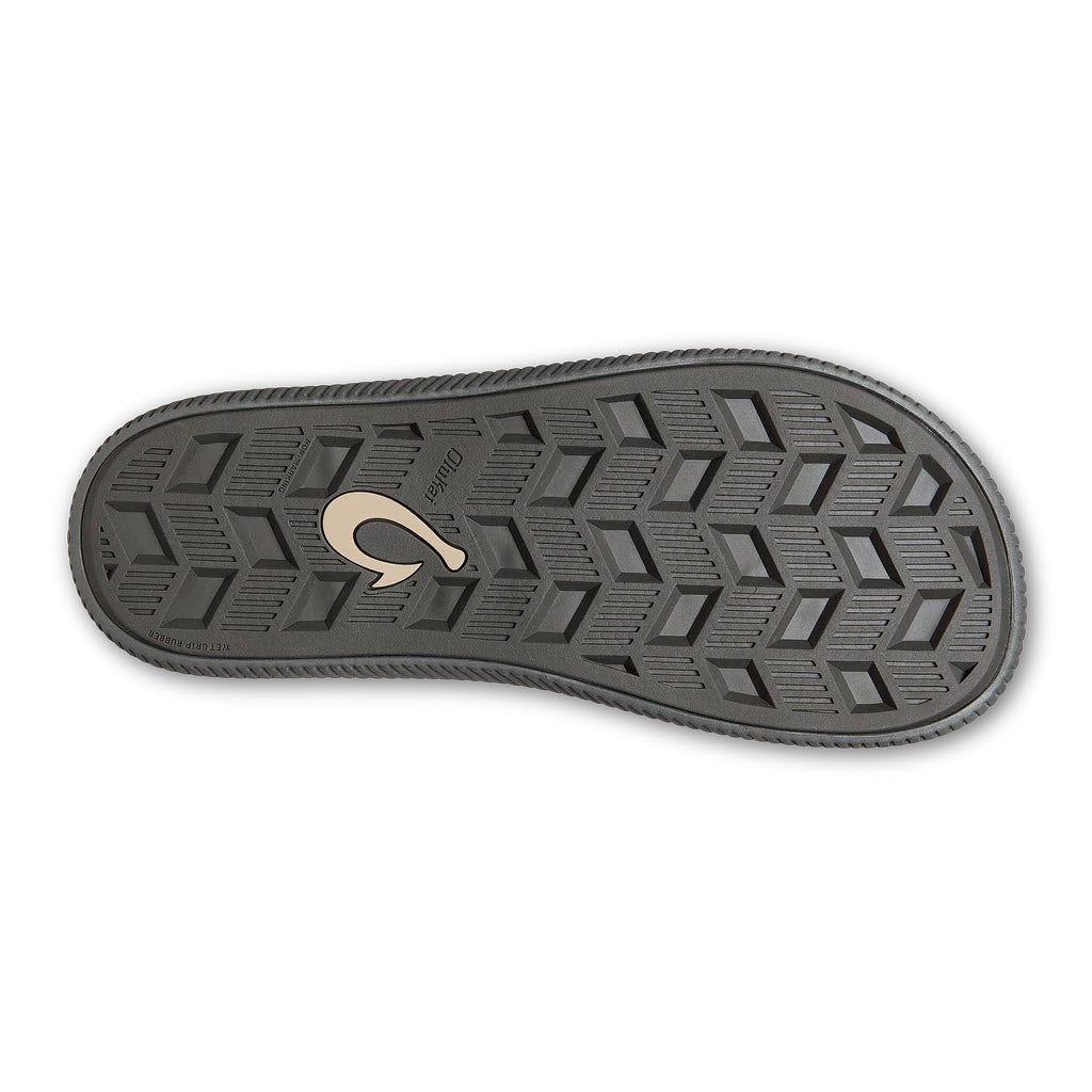 The sole of an Olukai Ulele Dark Shadow - Mens water-friendly sandal with a geometric tread pattern and a logo in the center.