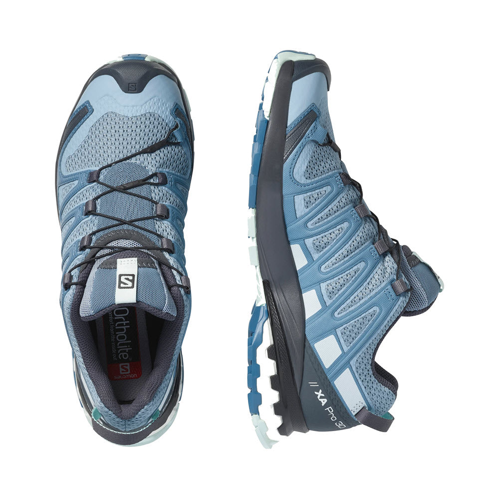 A pair of blue and gray Salomon XA Pro 3D V8 hiking shoes displayed from above, one shoe flipped to reveal the Contagrip sole.