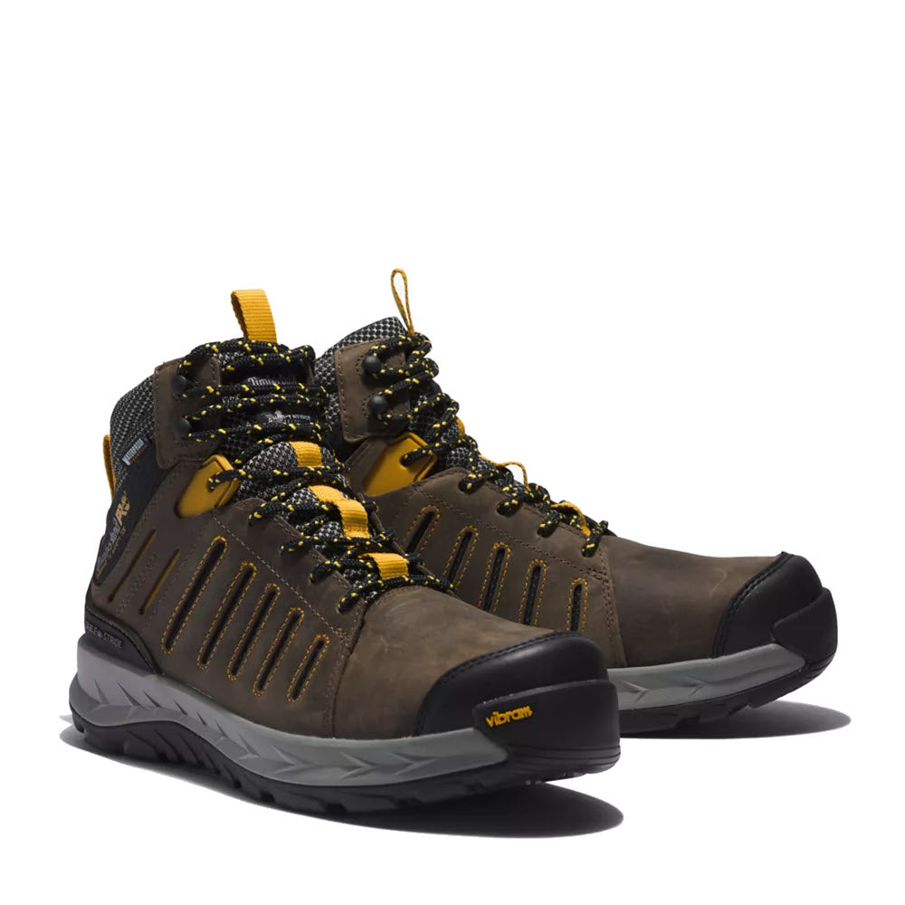 A pair of Timberland TIMBERLAND PRO TRAILWIND COMP TOE WP BOOT - MENS brown hiking boots with yellow laces, a vibram sole, and waterproof construction.