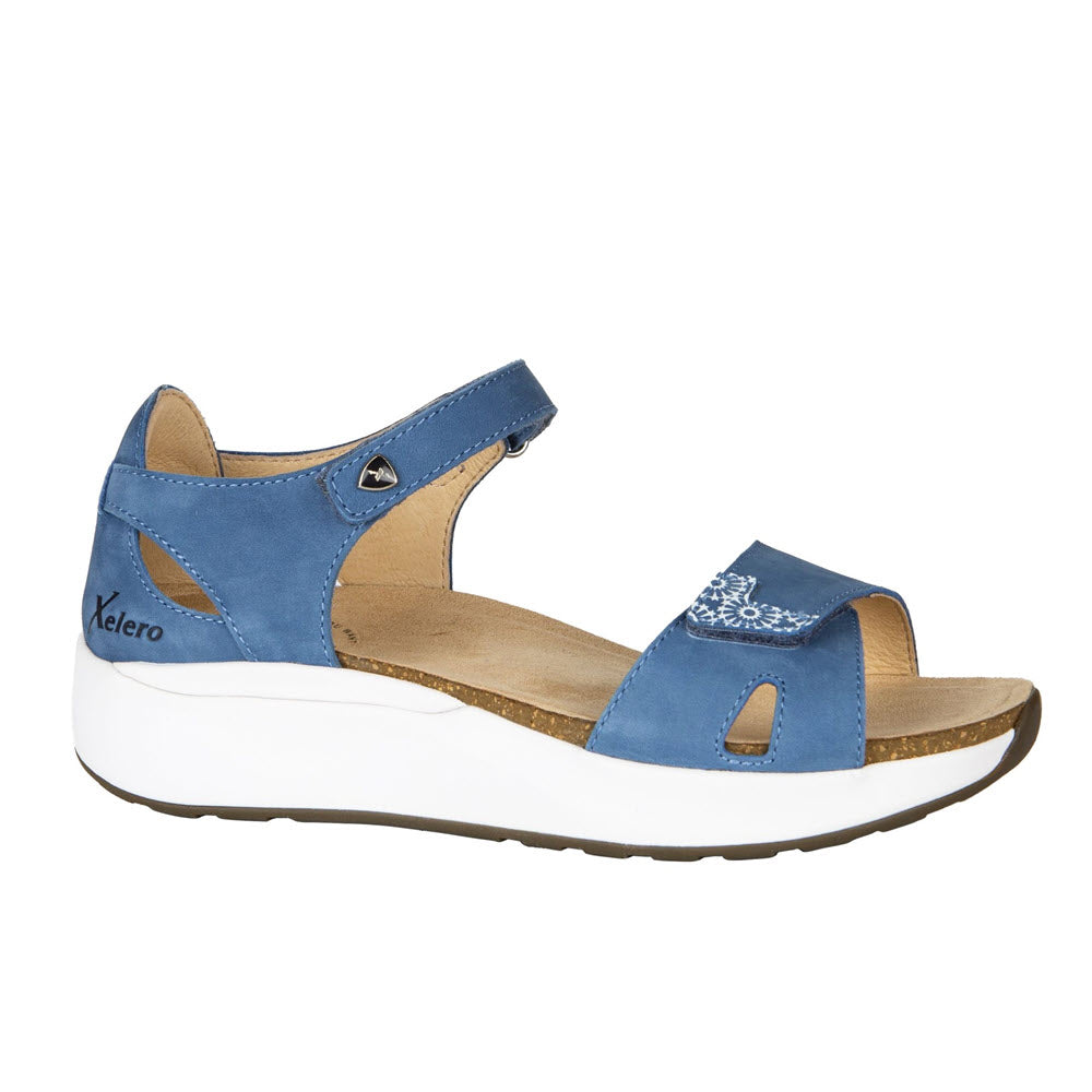 Blue and tan women's Xelero Santorini Denim Nubuck sandal with velcro strap, slip-resistant white sole, and comfortable footbeds.