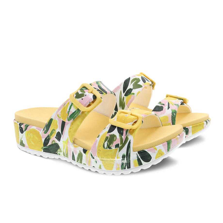 A pair of DANSKO KANDI LEMONS - WOMENS featuring a lemon and leaf pattern with a yellow sole and adjustable straps, designed with Dansko Natural Arch technology for extra comfort.