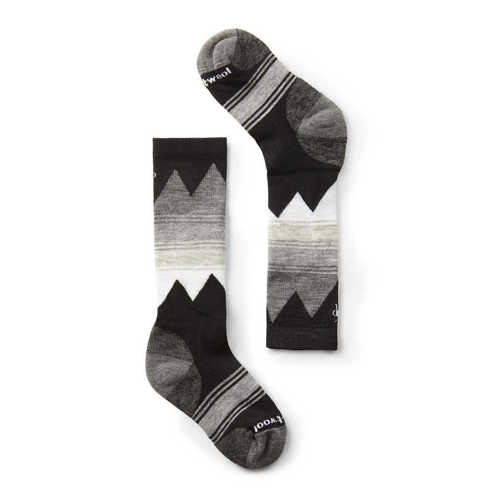 A pair of Smartwool Kids Ski Light OTC Socks in black, gray, and white geometric patterns, displayed against a white background.