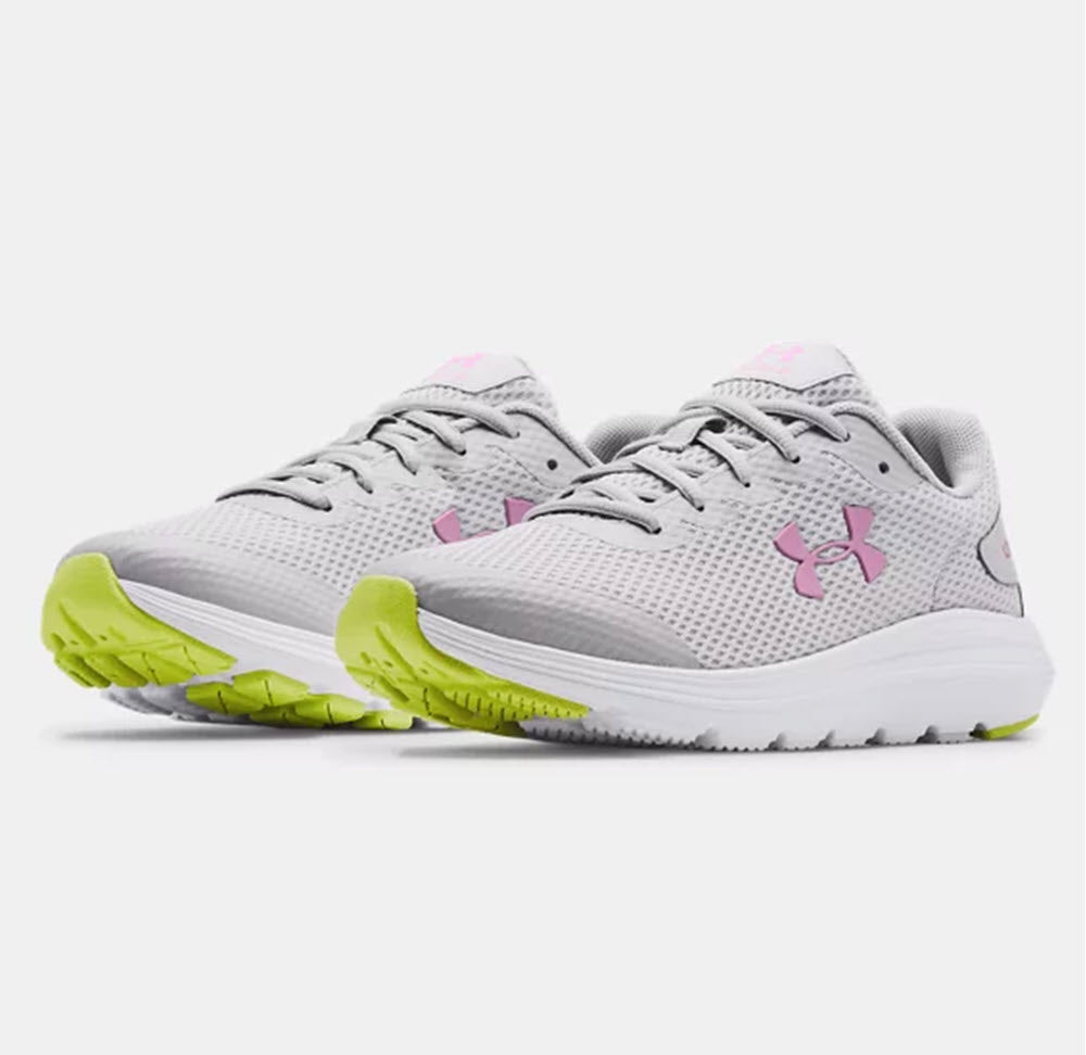 A pair of grey Under Armour Surge 2 GS Mod Grey running shoes with pink logos and lime green accents, featuring lightweight breathable mesh.