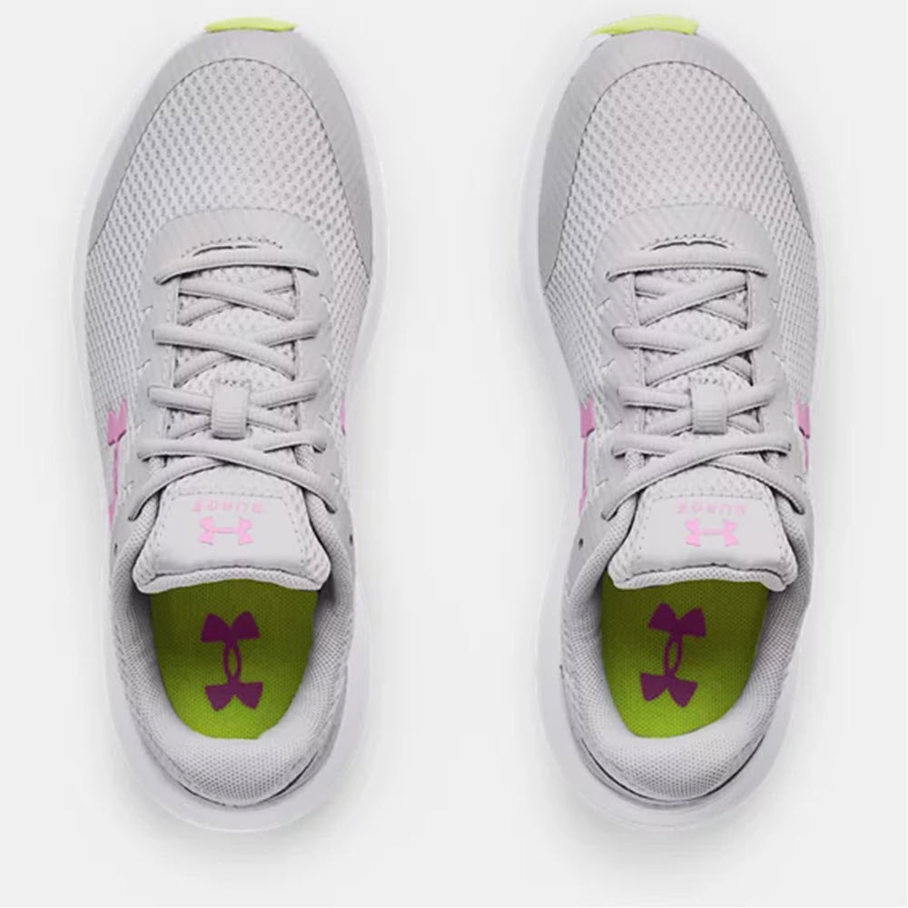 A pair of gray Under Armour Surge 2 GS Mod Grey running shoes with pink accents and a lime green insole, featuring a visible brand logo on the tongue.