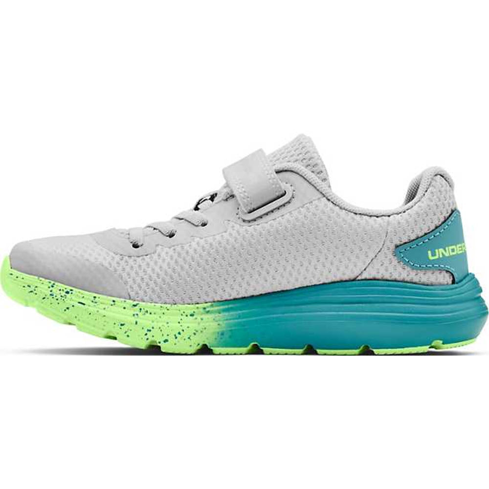 Side view of an Under Armour Surge 2 AC Halo Grey - Kids athletic shoe with a green sole and velcro strap.