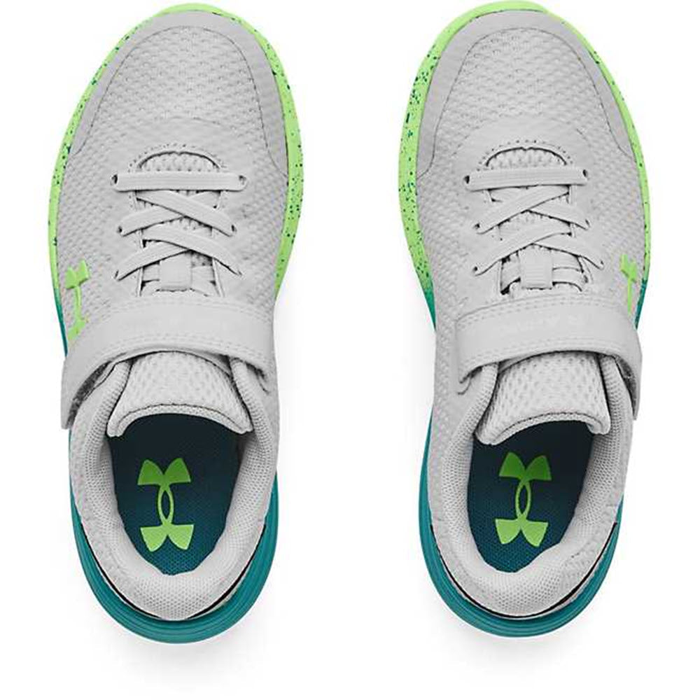 A pair of gray Under Armour Surge 2 AC Halo Grey running shoes with green accents and a visible brand logo on the insole.