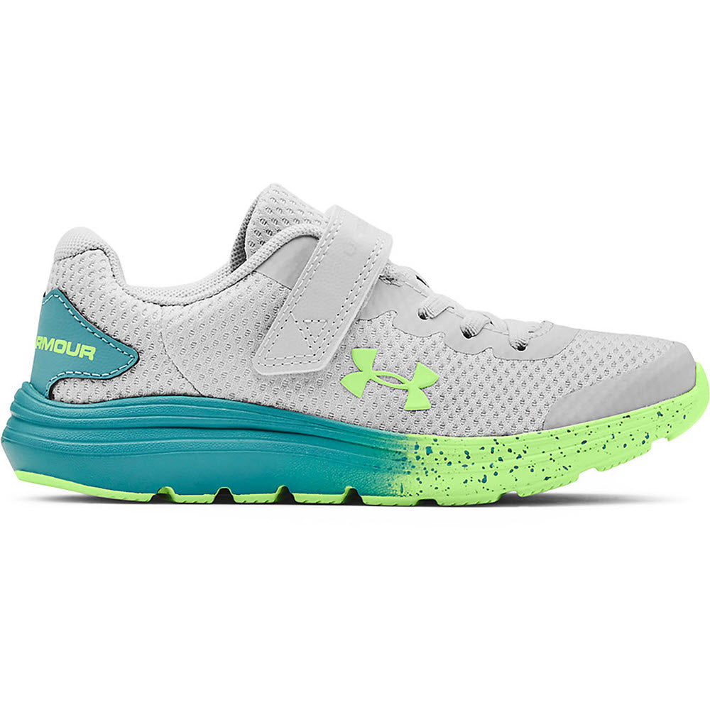 A kid's athletic shoe featuring a cushioned EVA midsole, this gray Under Armour Surge 2 AC Halo Grey sneaker comes with a velcro strap and green accents.