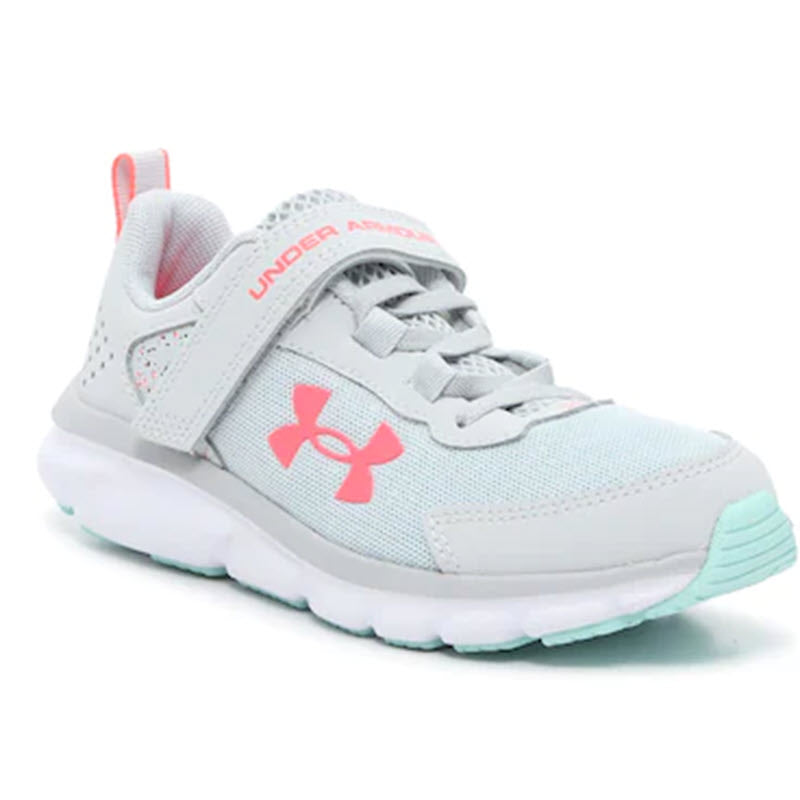 White and pink Under Armour Assert 9 Grey kid&#39;s athletic shoe with lace-up closure, lightweight mesh upper, and logo on the side.
