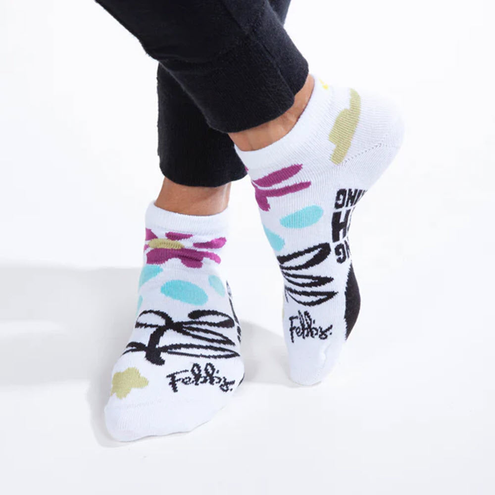 Person wearing colorful ankle socks with abstract patterns and text designs, crafted in partnership with Worlds Softest for at-risk women and children advocacy, Made in USA.