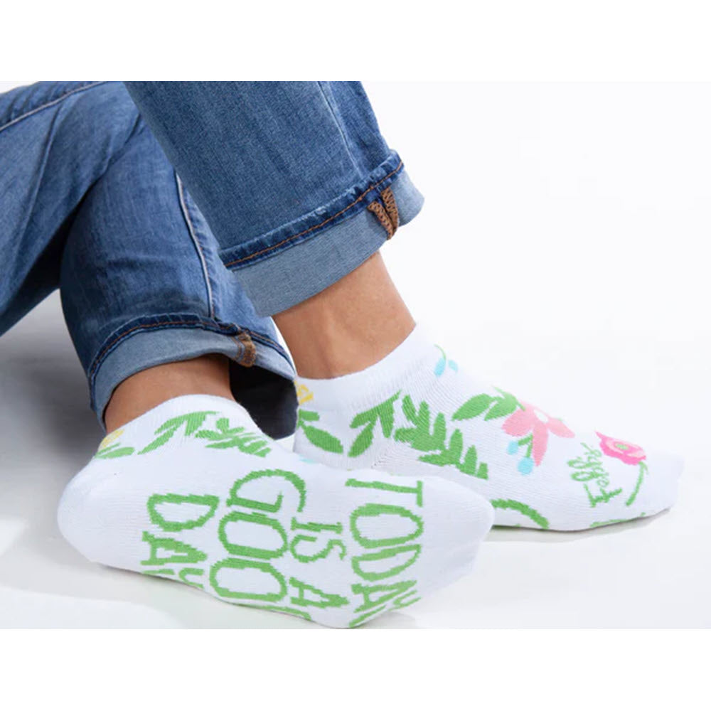 A person wearing Worlds Softest Today is a Good Day Low Cut Socks with floral patterns and the word &quot;AWAKE&quot; printed on them, from Febb&#39;s Boutique—a brand supporting at-risk women and children—sits with crossed ankles, only.