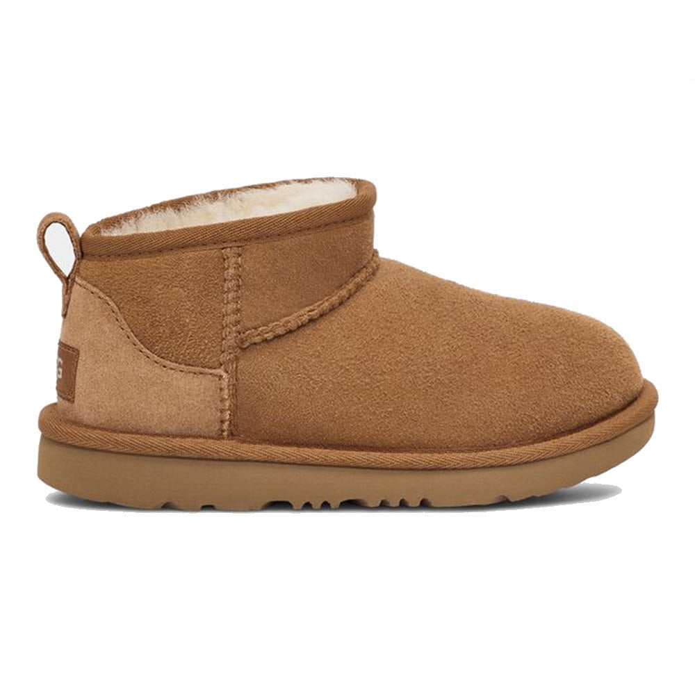 A single brown UGG Classic Ultra Mini Chestnut - Kids ankle-high boot with a plush sheepskin lining and a flat rubber sole, viewed from the side.