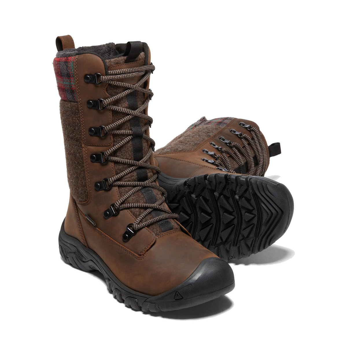 A pair of KEEN GRETA TALL BOOT BROWN - WOMENS with plaid detailing, rugged laces, and thick treaded soles featuring KEEN.DRY membrane, isolated on a white background.