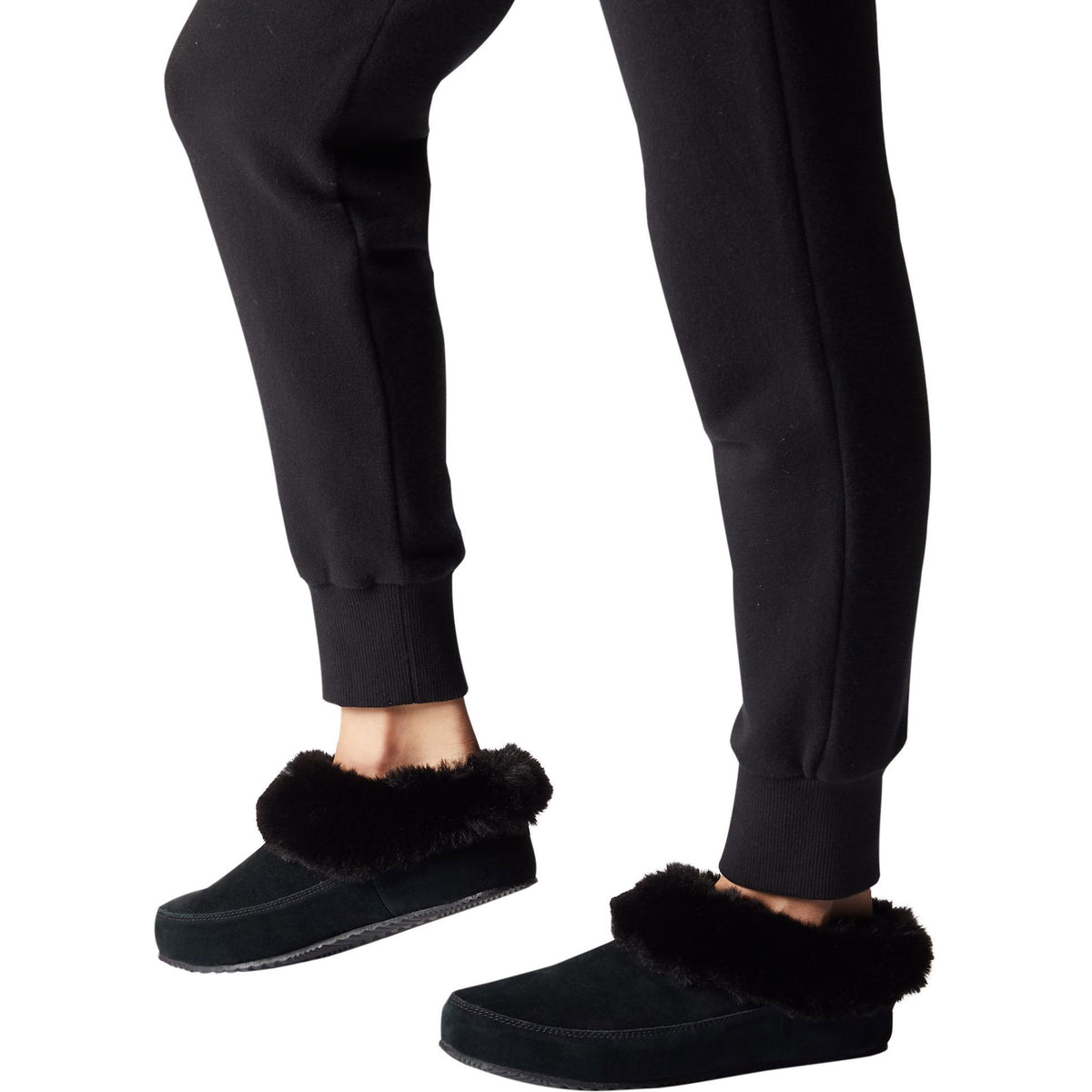A person standing in black trousers paired with Sorel GO Coffee Run Black slippers designed with a tough sole for quick trips outside.
