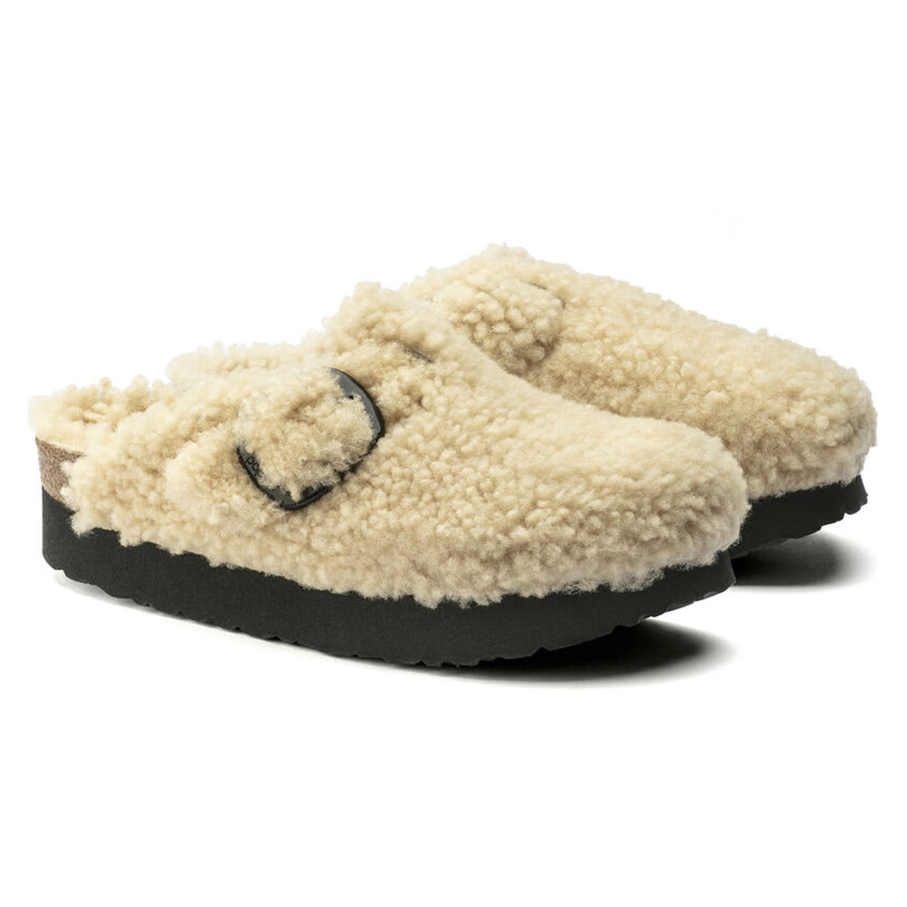 A pair of Birkenstock Boston Platform Big Buckle Teddy Eggshell Shearling - Womens with smiley faces on the uppers and thick platform soles, isolated on a white background.