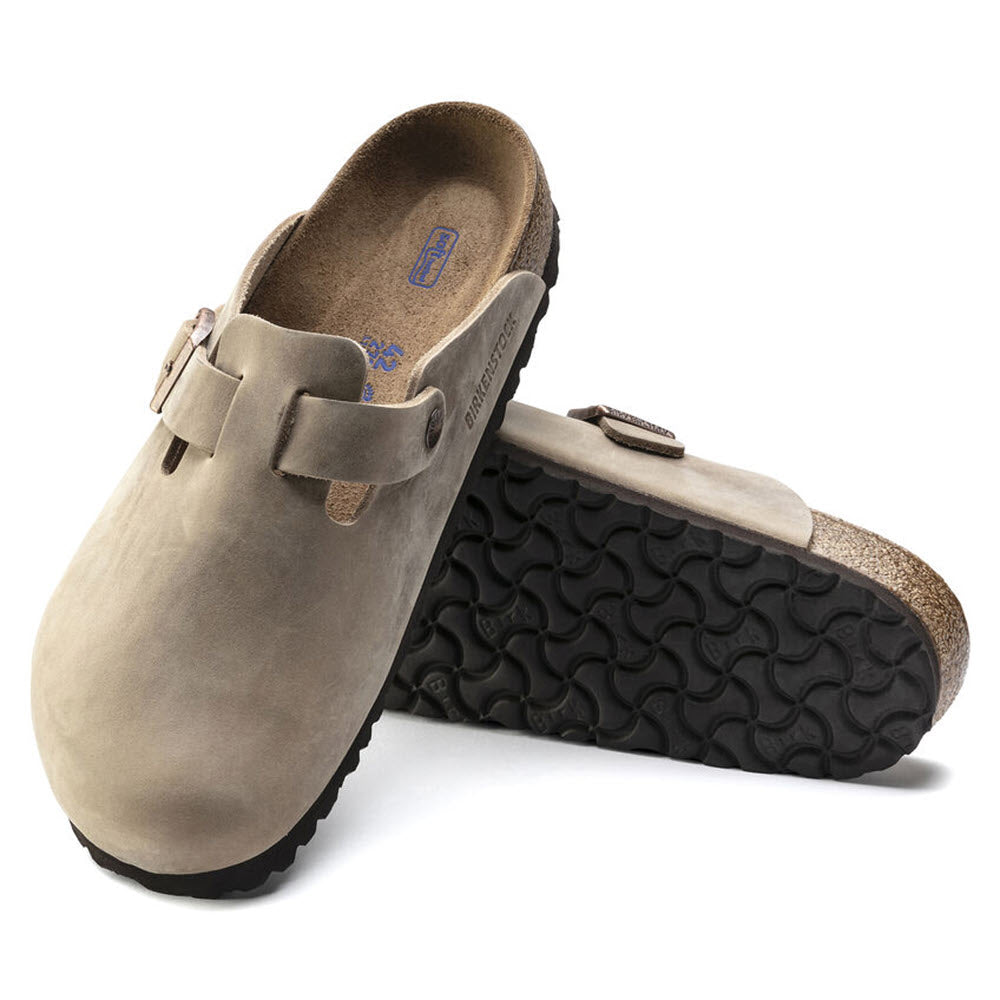 A pair of Birkenstock Boston Tobacco Leather - Adults clogs with adjustable straps and contoured cork soles.