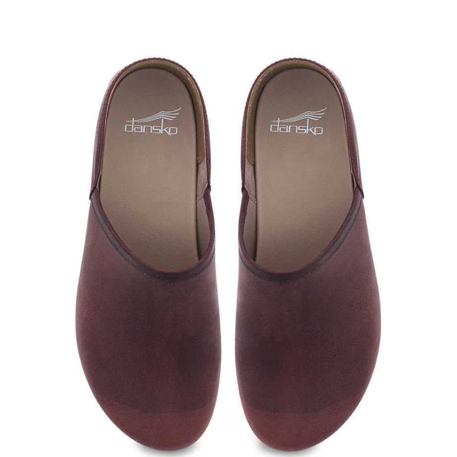 A pair of brown Dansko Brenna Ruby Oiled Pull Up clogs with odor control, viewed from the front, isolated on a white background.