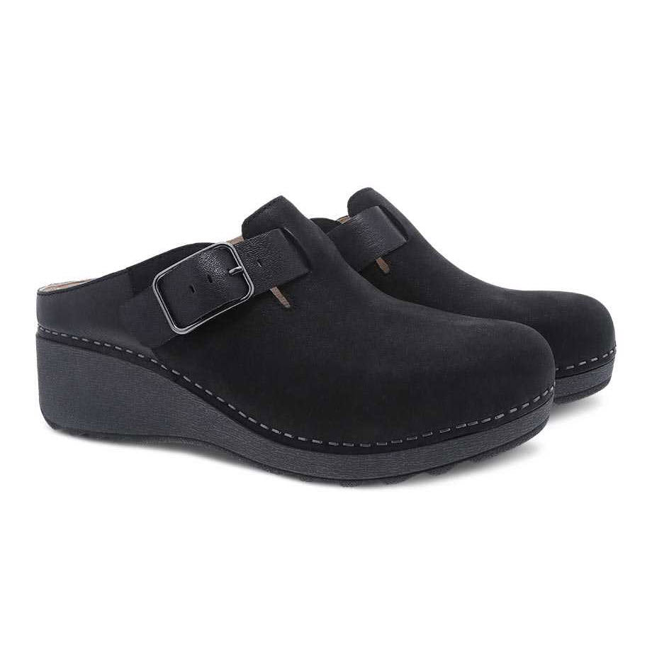 A pair of black Dansko Caia buckle clogs on a white background.