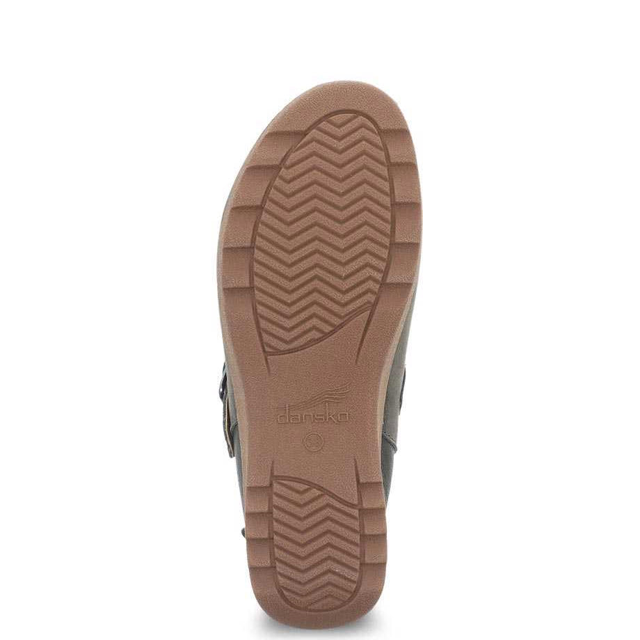 The sole of a brown Dansko Caia Taupe Milled casual mule displaying the tread pattern and brand logo.