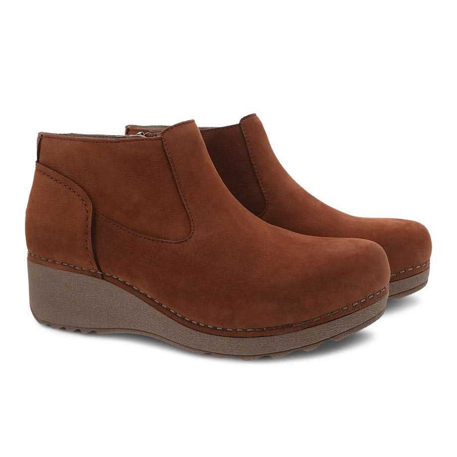 A pair of brown nubuck leather wedge ankle boots with side zippers, the Dansko Charlene Ginger Milled - Womens, against a white background.