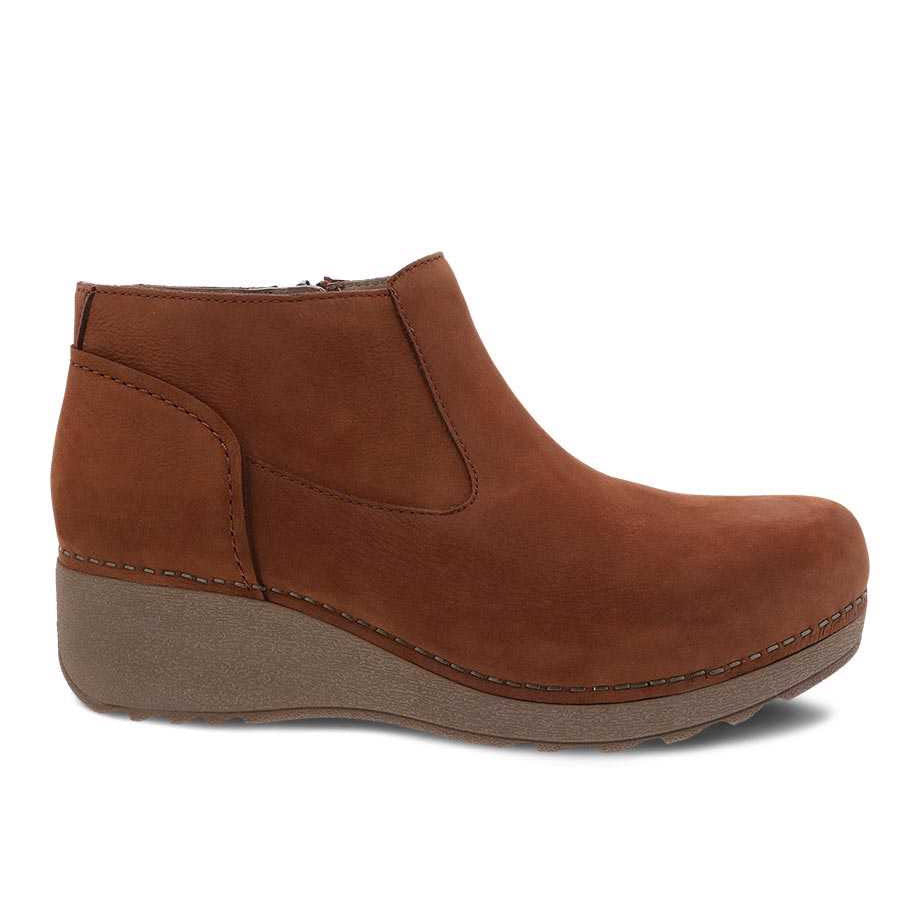 A brown nubuck leather Dansko Charlene Ginger Milled ankle boot with a wedge heel and visible stitching, displayed against a white background.