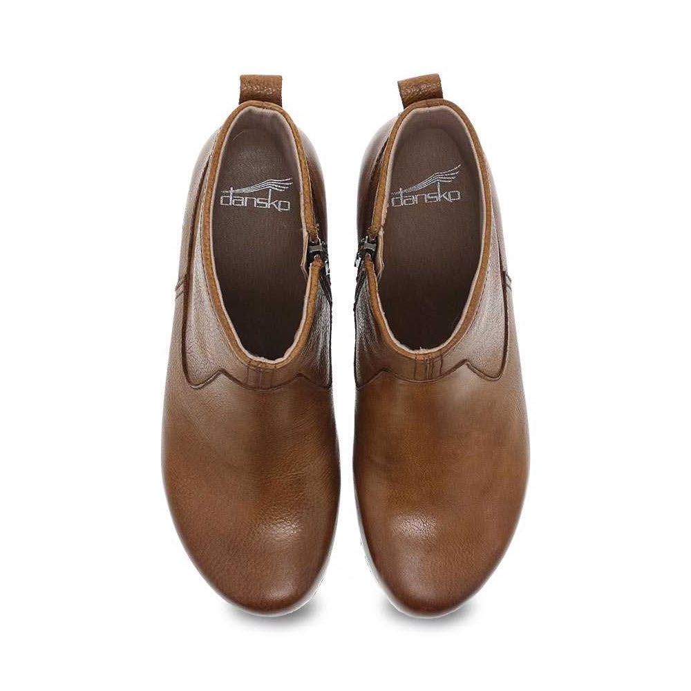 A pair of brown Dansko Sarah Tan Milled Burnished leather stylish booties, viewed from above, isolated on a white background.