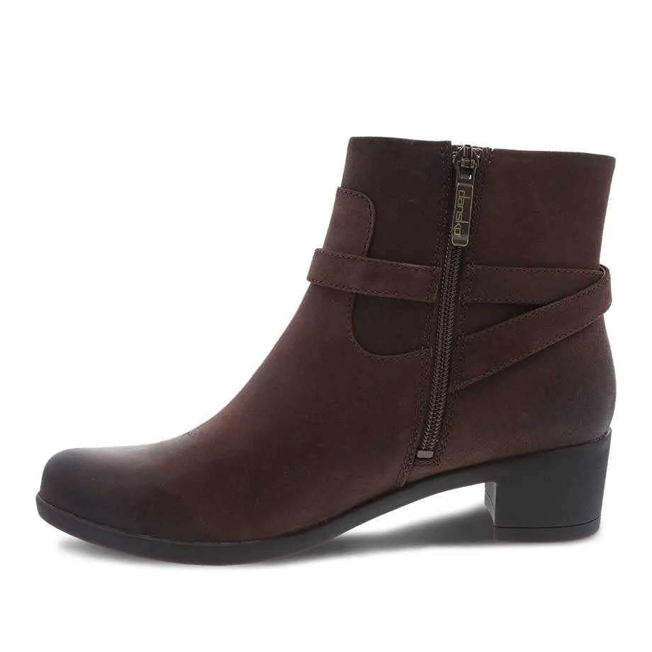 Dansko Cagney brown burnished ankle boot with a strap detail and side zipper, displayed against a white background.