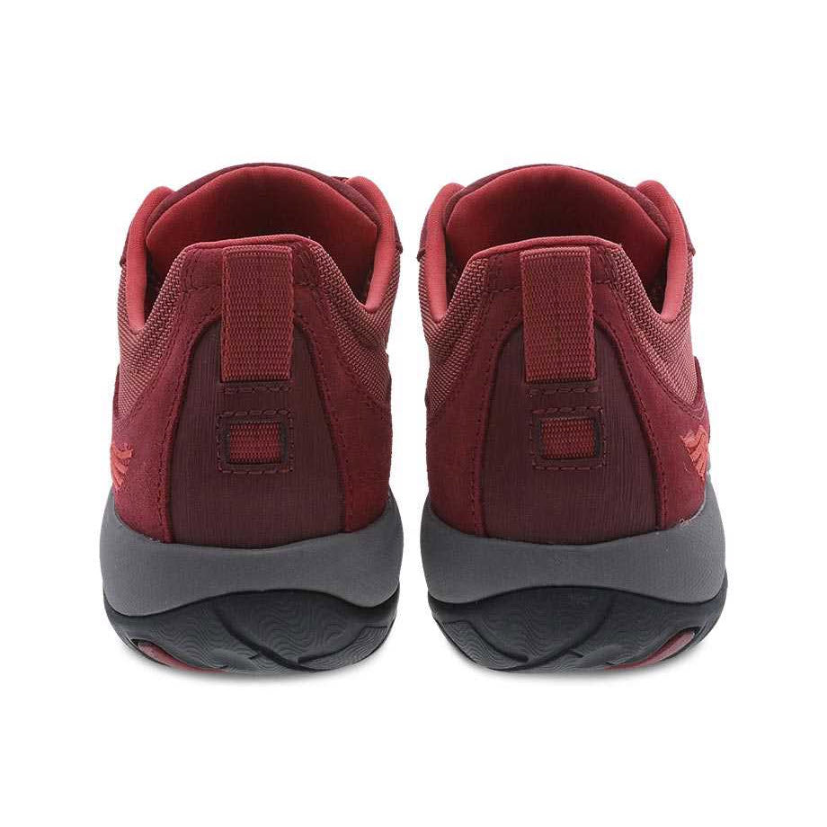 A pair of maroon walking shoes with grey Vibram rubber outsoles viewed from the back. -&gt; A pair of red burnished Dansko Paisley walking shoes with grey Vibram rubber outsoles viewed from the back.