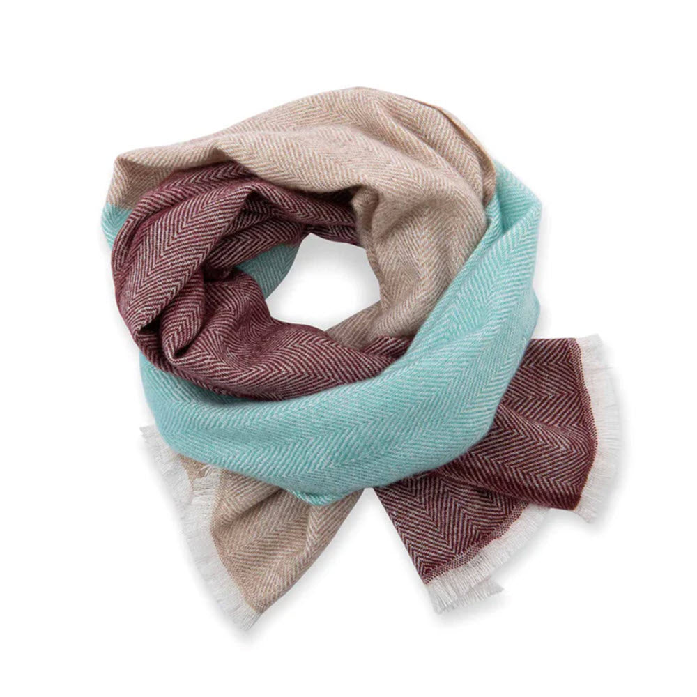 A PISTIL KIN scarf with a colorblocked herringbone pattern, featuring shades of turquoise, red, and beige, neatly folded on a white background.