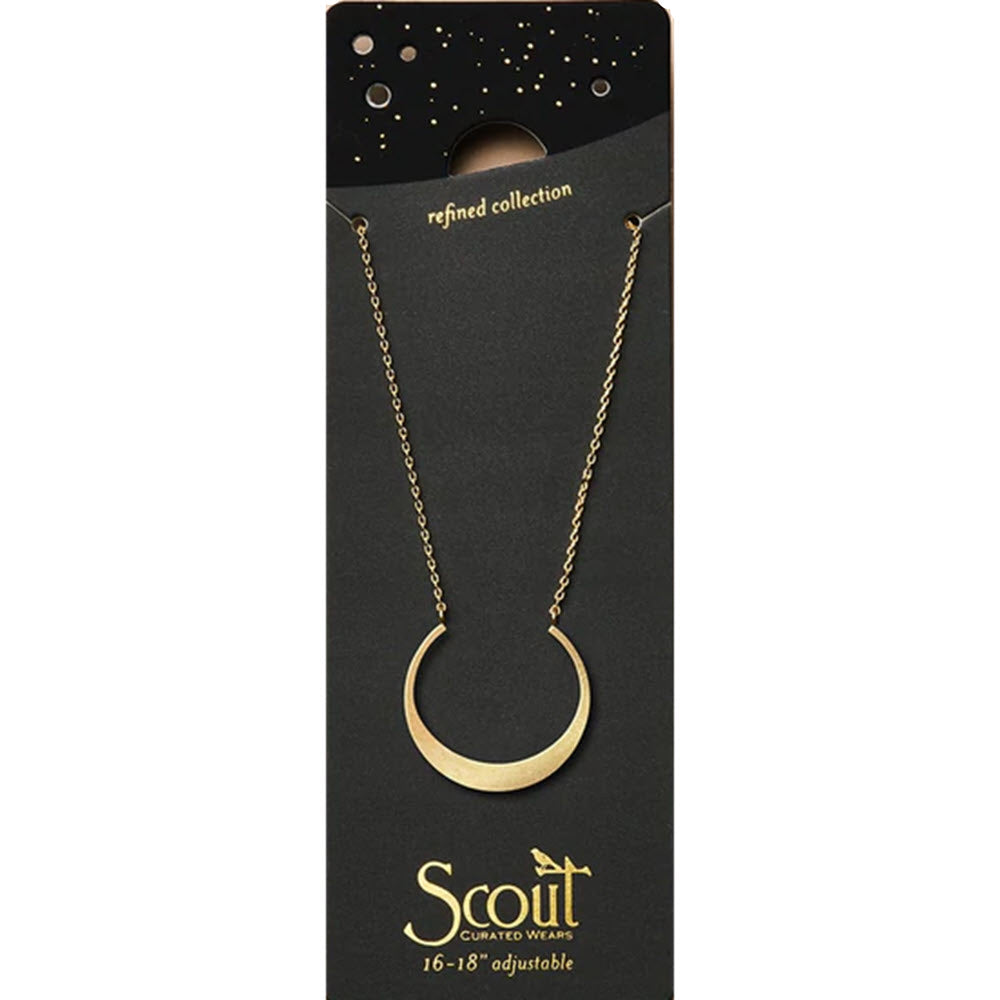 Gold crescent pendant on a chain, displayed on a black packaging with star motifs and the brand name 'Scout'.