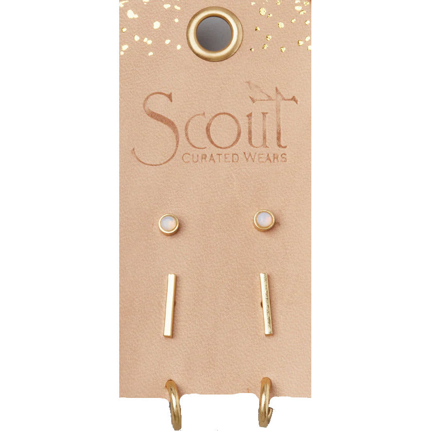 A display card with the logo "Scout" featuring the SCOUT SCARLETT STUD TRIO GOLD, a pair of minimalist earrings and two bar-shaped metallic accents that are nickel and cadmium free.