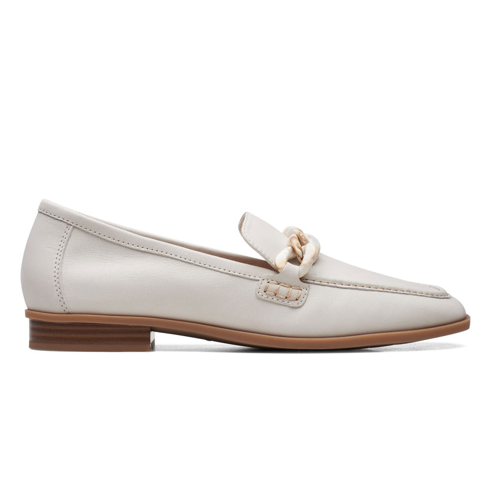 A white leather Clarks Sarafyna Iris loafer with a bow detail on the vamp and a low brown heel, isolated on a white background.