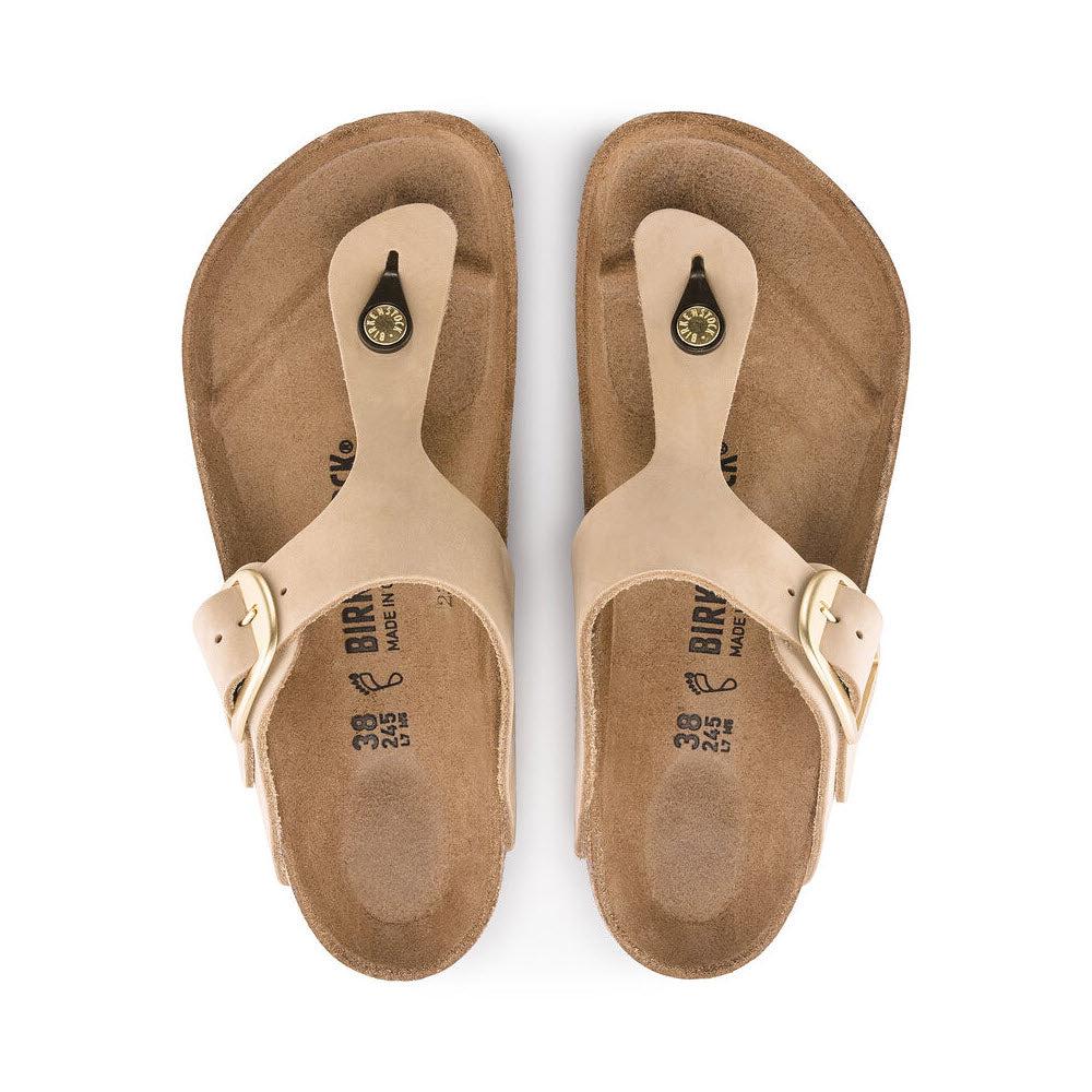 A pair of beige BIRKENSTOCK GIZEH BIG BUCKLE SANDCASTLE sandals with adjustable ankle straps and nubuck leather footbeds, viewed from above on a white background.
