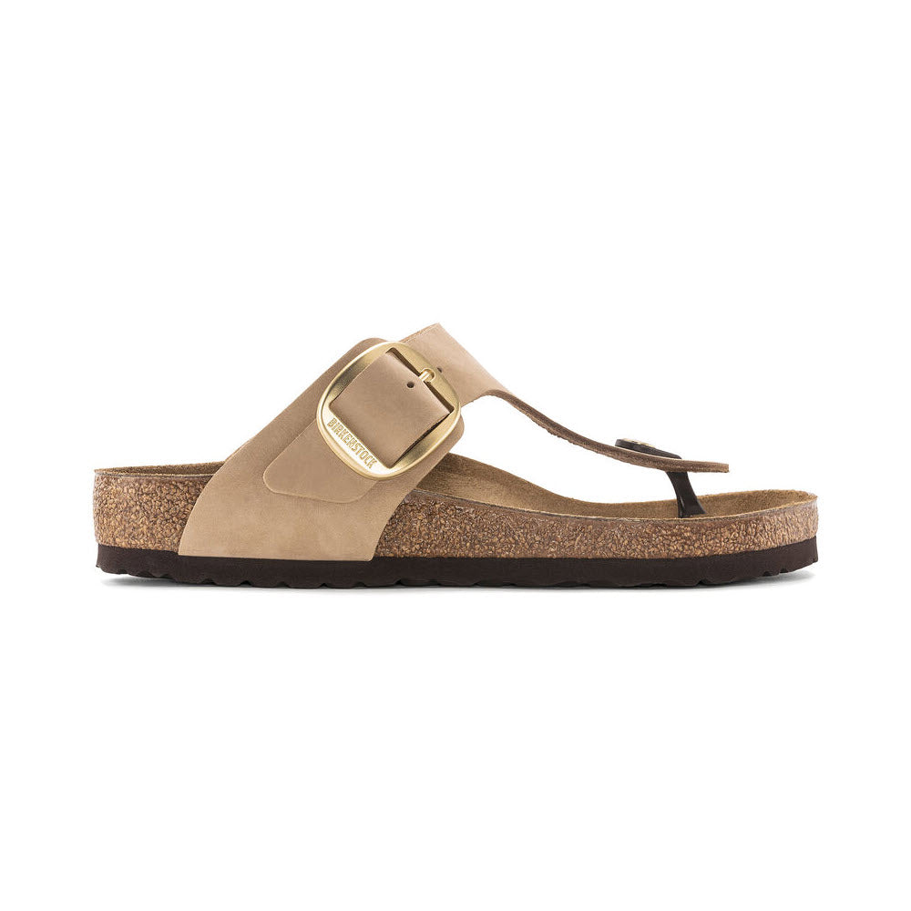 Side view of a single beige nubuck leather Birkenstock Gizeh Big Buckle sandcastle sandal with a cork sole on a white background.