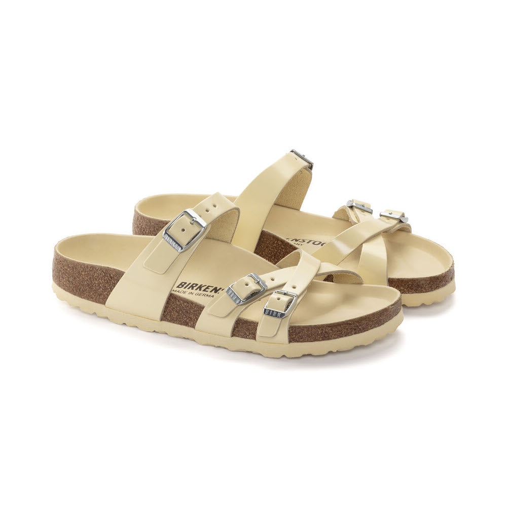 A pair of beige Birkenstock Franca Hex High Shine Butter sandals with adjustable straps and contoured cork-latex footbed isolated on a white background.