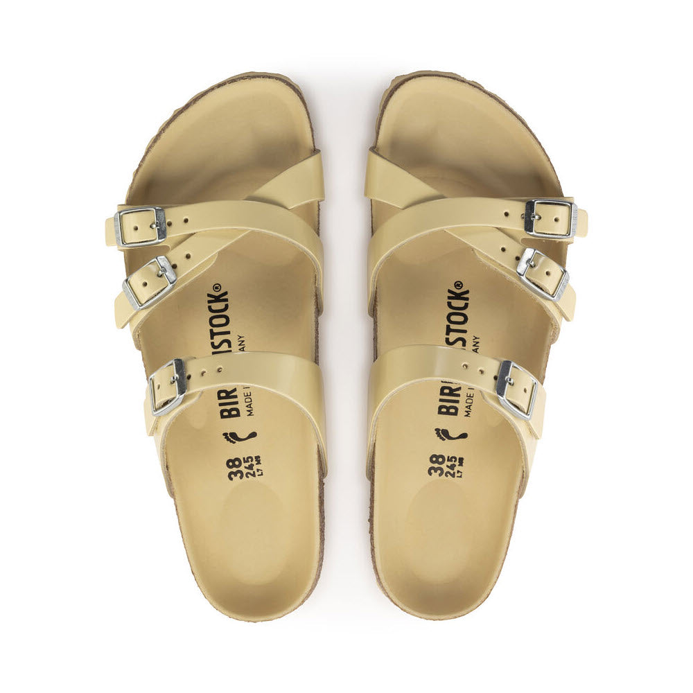 A pair of natural leather Birkenstock Franca Hex High Shine Butter sandals with adjustable straps and a contoured cork-latex footbed, viewed from above, isolated on a white background.
