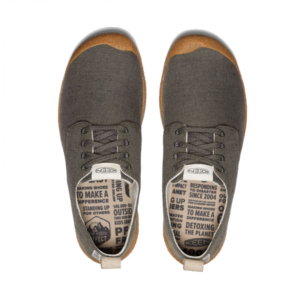 A pair of Keen Mosey Derby Canvas Black Olive sneakers with text printed on the tongue, viewed from above, featuring a soft-yet-grippy outsole.