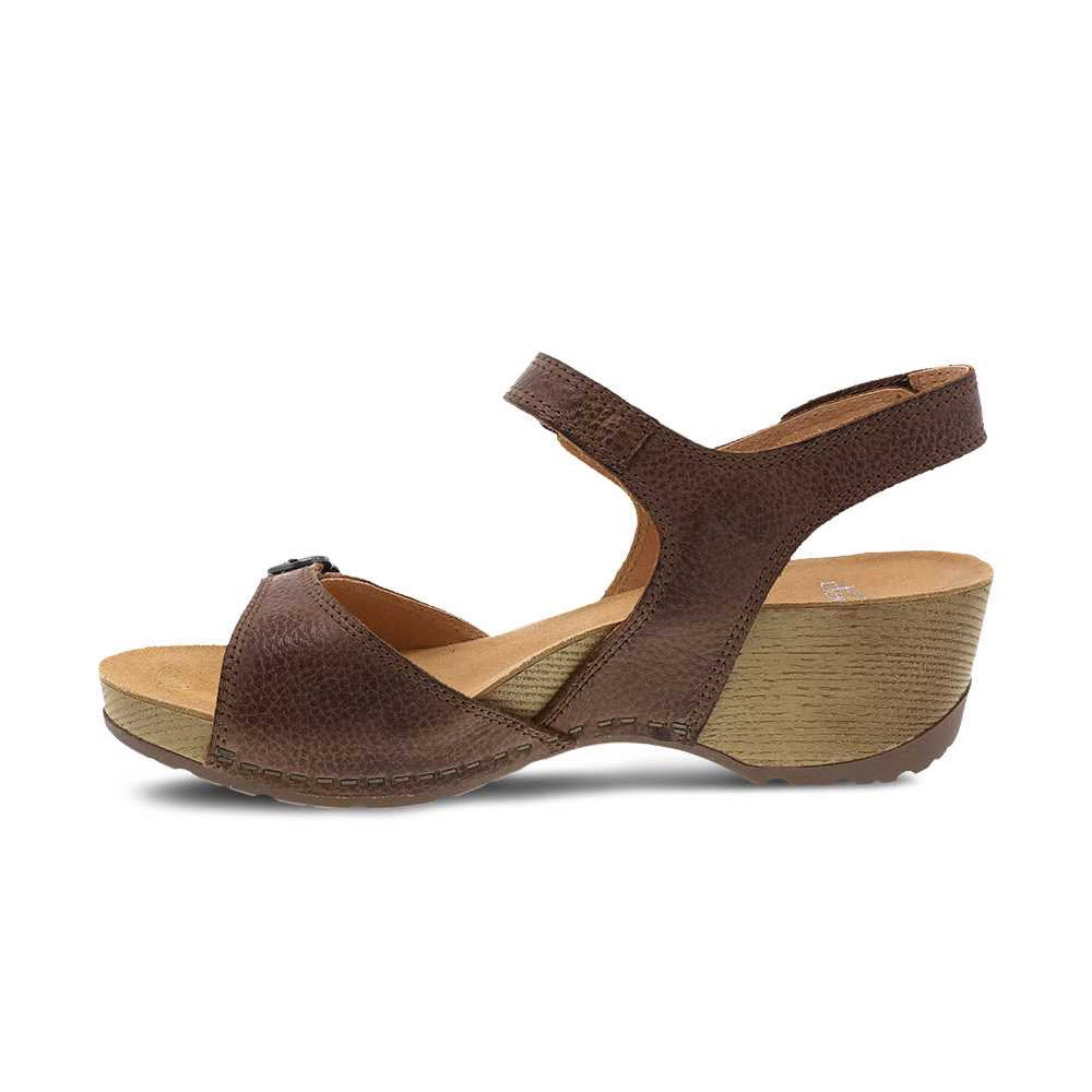 A Dansko Tricia Brown wedge sandal with a velcro strap and a memory foam footbed, displayed against a white background.
