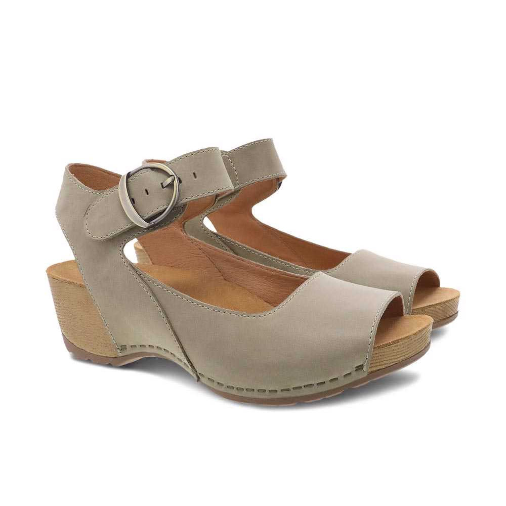 A pair of Dansko Tiana Khaki Nubuck women&#39;s sandals with chunky wooden heels, an ankle strap, and a buckle closure on a white background.