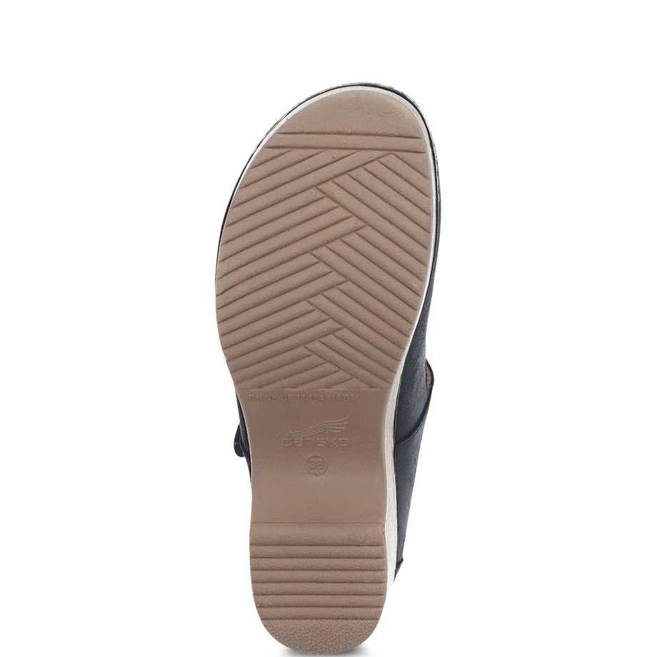 Bottom view of a Dansko shoe showing a beige sole with diagonal and horizontal tread patterns, a visible brand imprint, and a 3M Scotchgard protector coating.