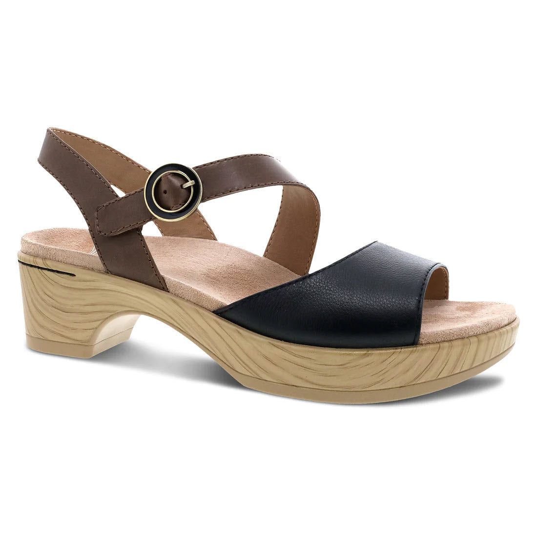 A Dansko women&#39;s black nappa leather sandal with asymmetrical black and tan straps, a circular buckle, and a wood-textured platform heel.